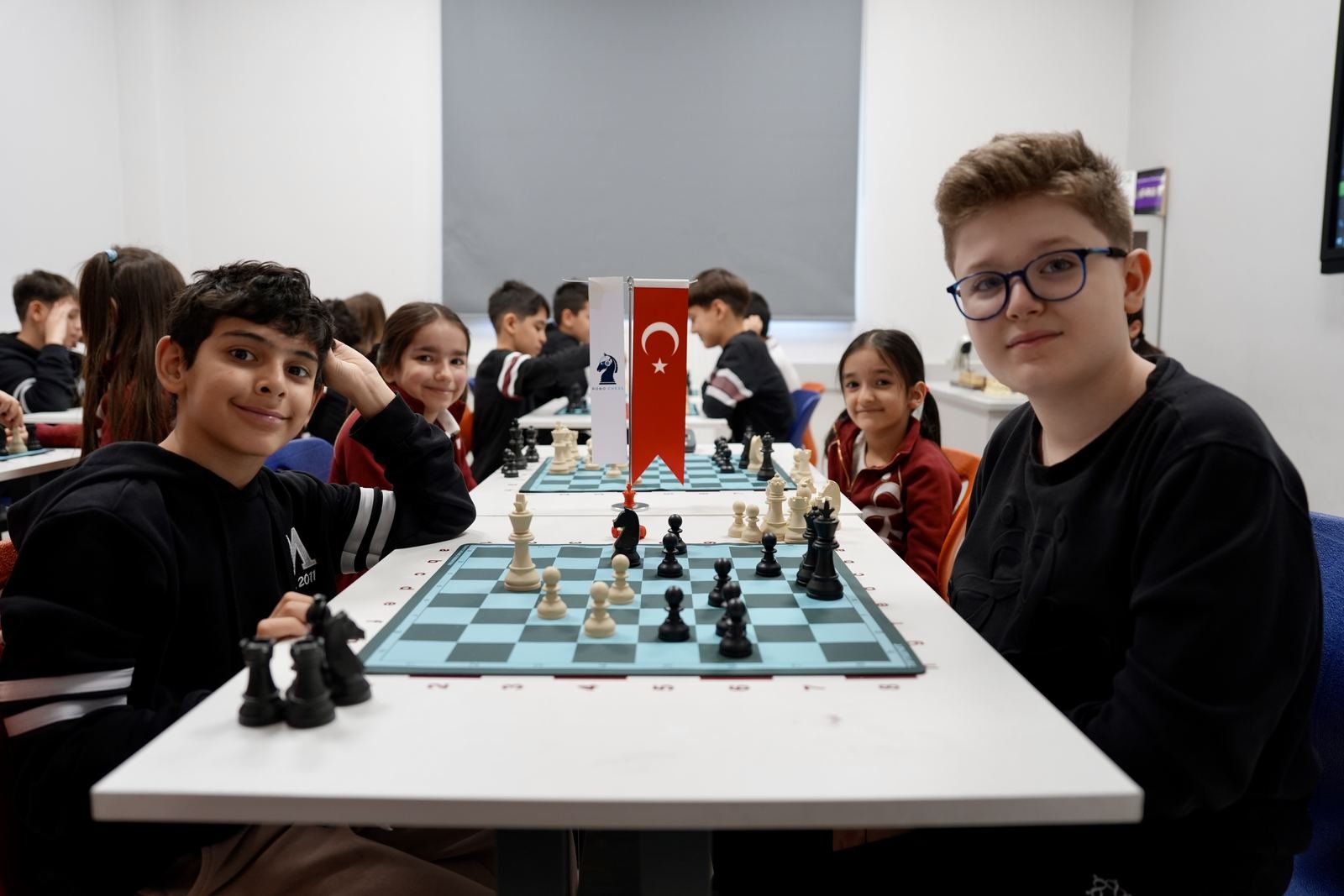 Akademide bir grup çocuk satranç tahtasının başında